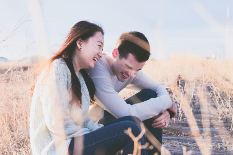 Giovane coppia che ride felice seduta in un campo